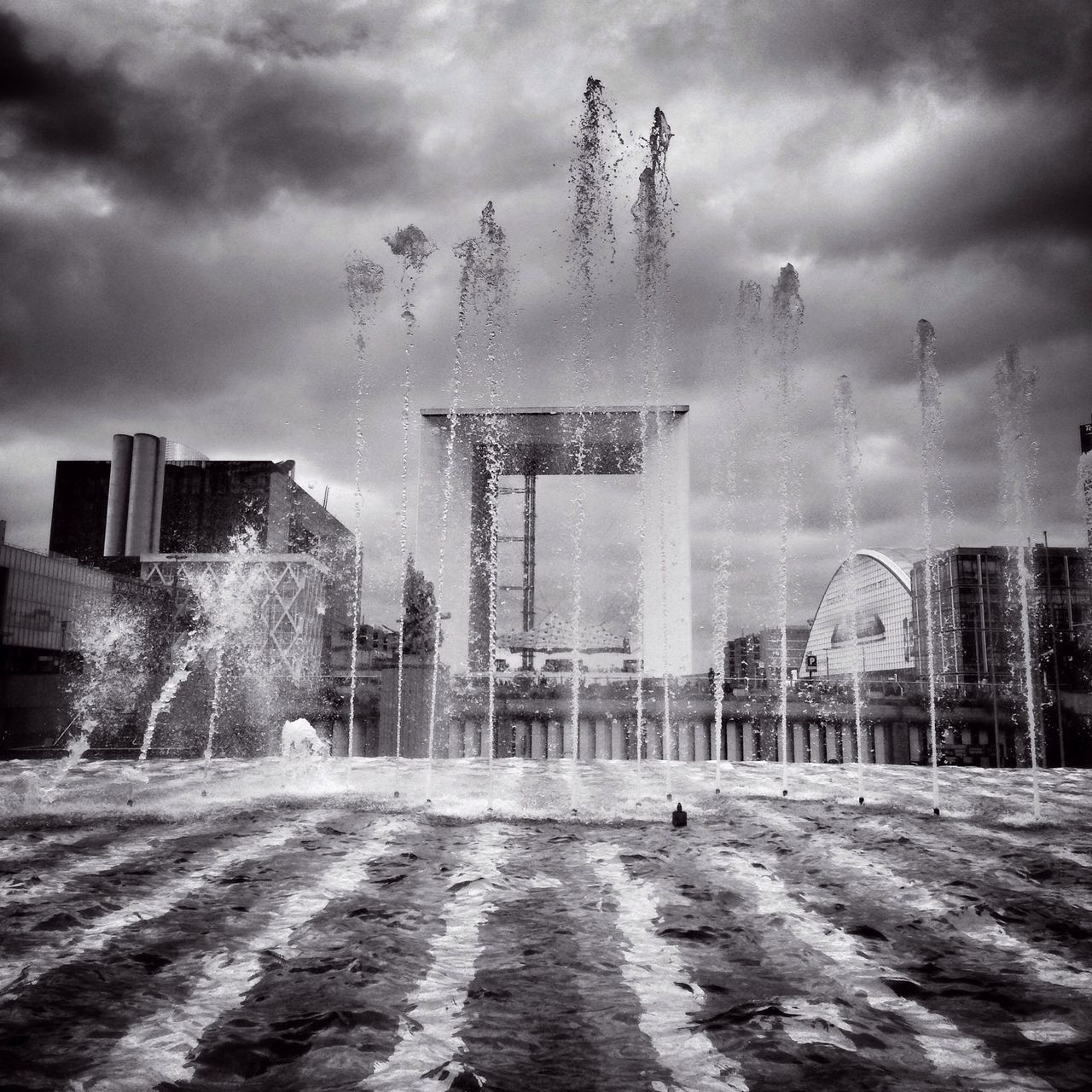 sky, cloud - sky, building exterior, cloudy, weather, architecture, built structure, men, storm cloud, lifestyles, motion, leisure activity, overcast, cloud, smoke - physical structure, fountain, medium group of people, building, person