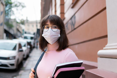 Portrait of young woman wearing mask standing outdoors