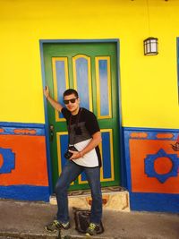 Full length of young man standing against yellow wall