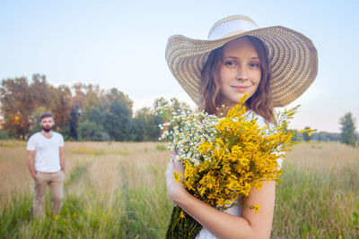 Portrait of smiling woman with yellow flowers on field