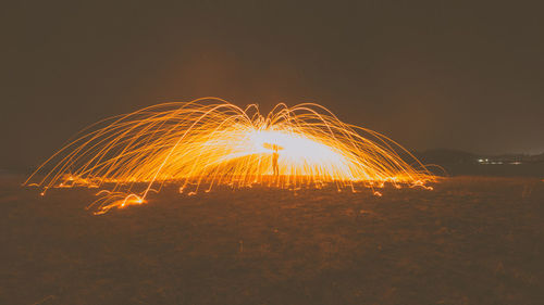 Light trails on field against sky at night