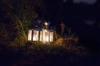 Close-up of illuminated lantern on field at night
