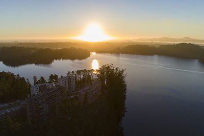 Scenic view of river by buildings against sky during sunset