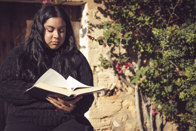 Young latin woman sitting reading a book