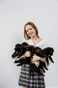 The girl holds black puppies in her hands.