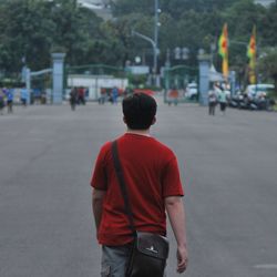 Rear view of man walking on road in city