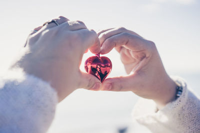 Close-up of woman hands holding heart shape with reflection