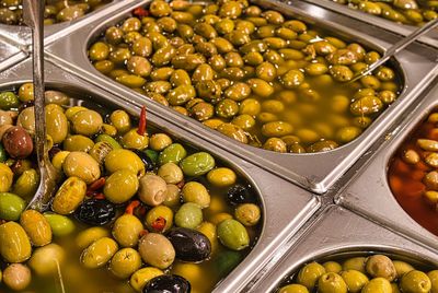 Green olives stuffed with red peppers on a store counter.