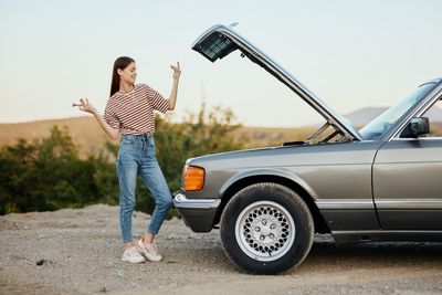 Side view of woman standing by car