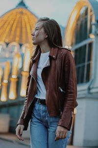 Low angle view of woman looking away while standing against building