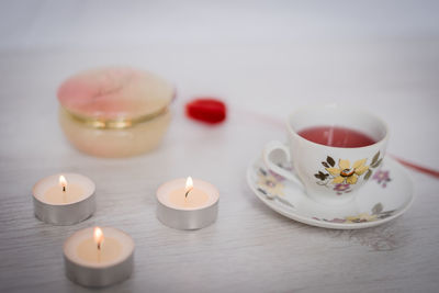 Close-up of lit tea light and drink on table