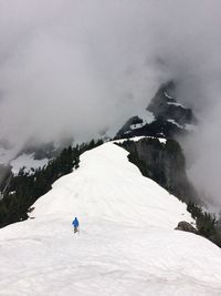 Rear view of man on snowcapped mountain against sky