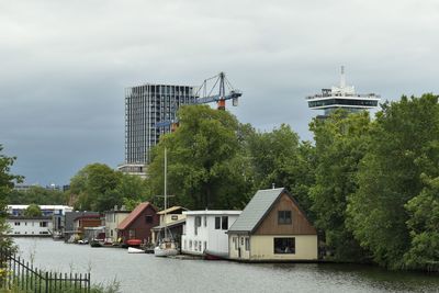 Buildings by river against sky