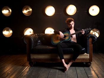 Rear view of man playing guitar on table