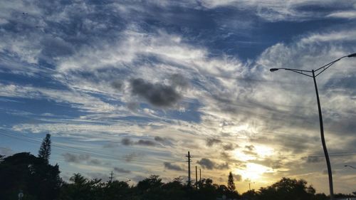 Low angle view of power lines against cloudy sky