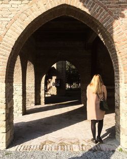 Full length of young woman standing against brick wall