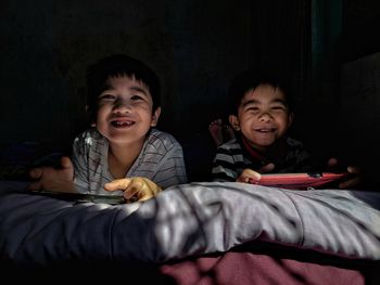 Portrait of siblings sitting on bed at home