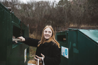 Portrait of smiling woman standing against trees