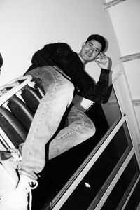 Low angle view of smiling man sitting on staircase at home