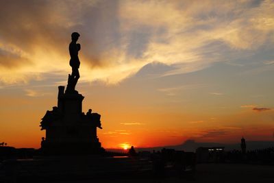 Silhouette of statue against cloudy sky during sunset