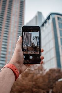 Midsection of man using mobile phone in city