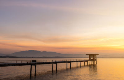 Pier over sea against sky during sunset