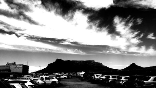 Cars in parking lot by city against sky