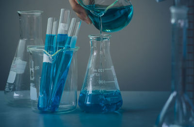 Cropped hand pouring chemical in flask at desk