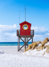 Lifeguard hut on beach against blue sky