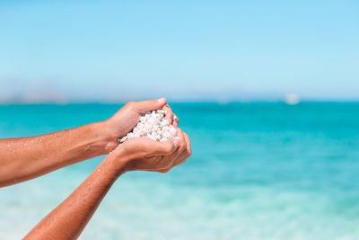 Close-up of hand on sea shore against sky