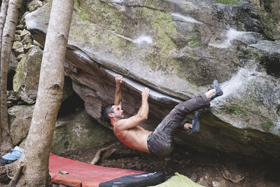 A male rock climber climbs a rock outdoors