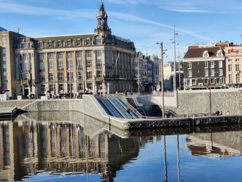 Reflection  in  amsterdam canal,  in front of cantral station  with blue sky
