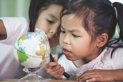 Friends looking at globe while studying at classroom