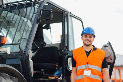 Portrait construction worker standing by crane