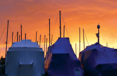 Sailboats moored in sea against sky during sunset