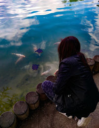 Rear view of woman sitting by lake