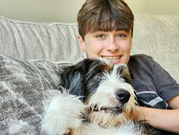 Cute teen boy holding dog on a couch.