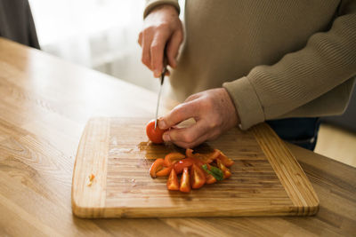 Cropped hands of man preparing food on cutting board