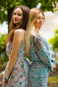 Portrait of friends standing back to back outdoors