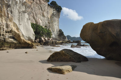 Rock formation on beach against sky