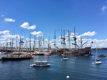 Boats moored at harbor against blue sky