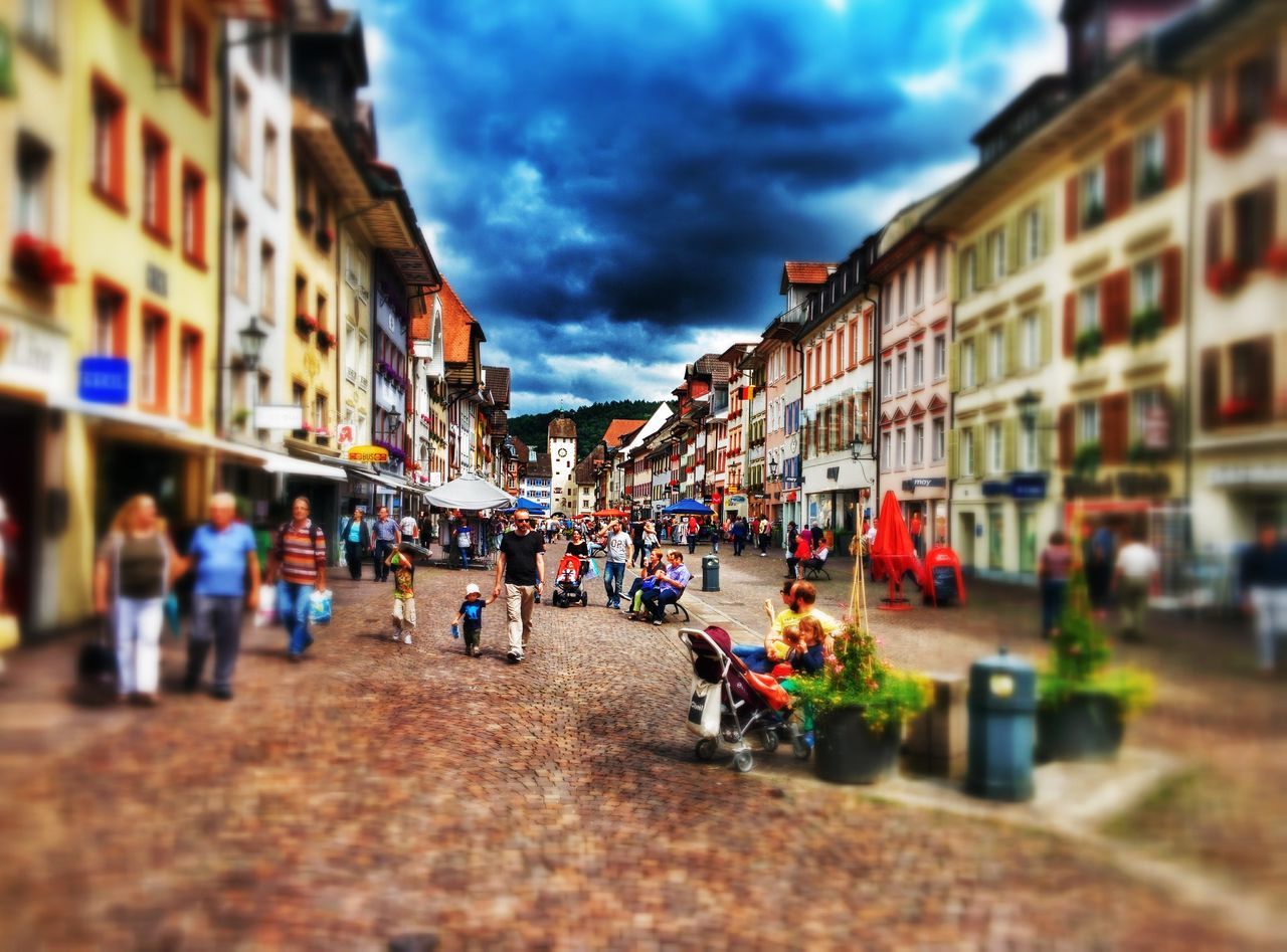 building exterior, architecture, built structure, street, sky, city, cloud - sky, large group of people, city life, residential structure, residential building, person, walking, cloud, road, men, cloudy, residential district, transportation