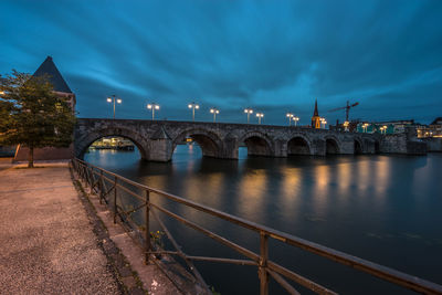 Illuminated bridge over river against sky in city at night