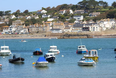 Sailboats moored on sea by buildings in city