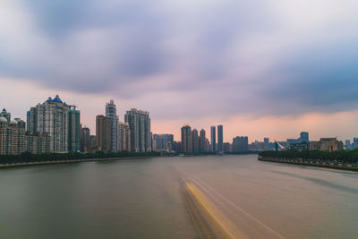 Modern buildings in city against sky during sunset