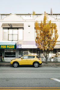 Yellow car on street against buildings