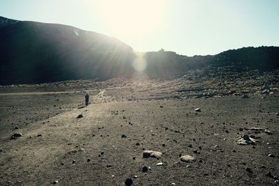 Rear view of man walking on mountain against clear sky