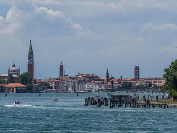 View of buildings at waterfront against cloudy sky