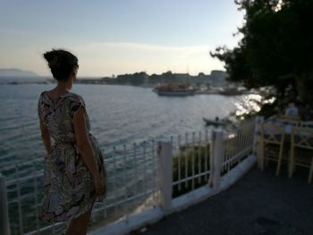 Rear view of woman standing by sea against sky