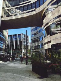 Rear view of people walking on street against modern buildings